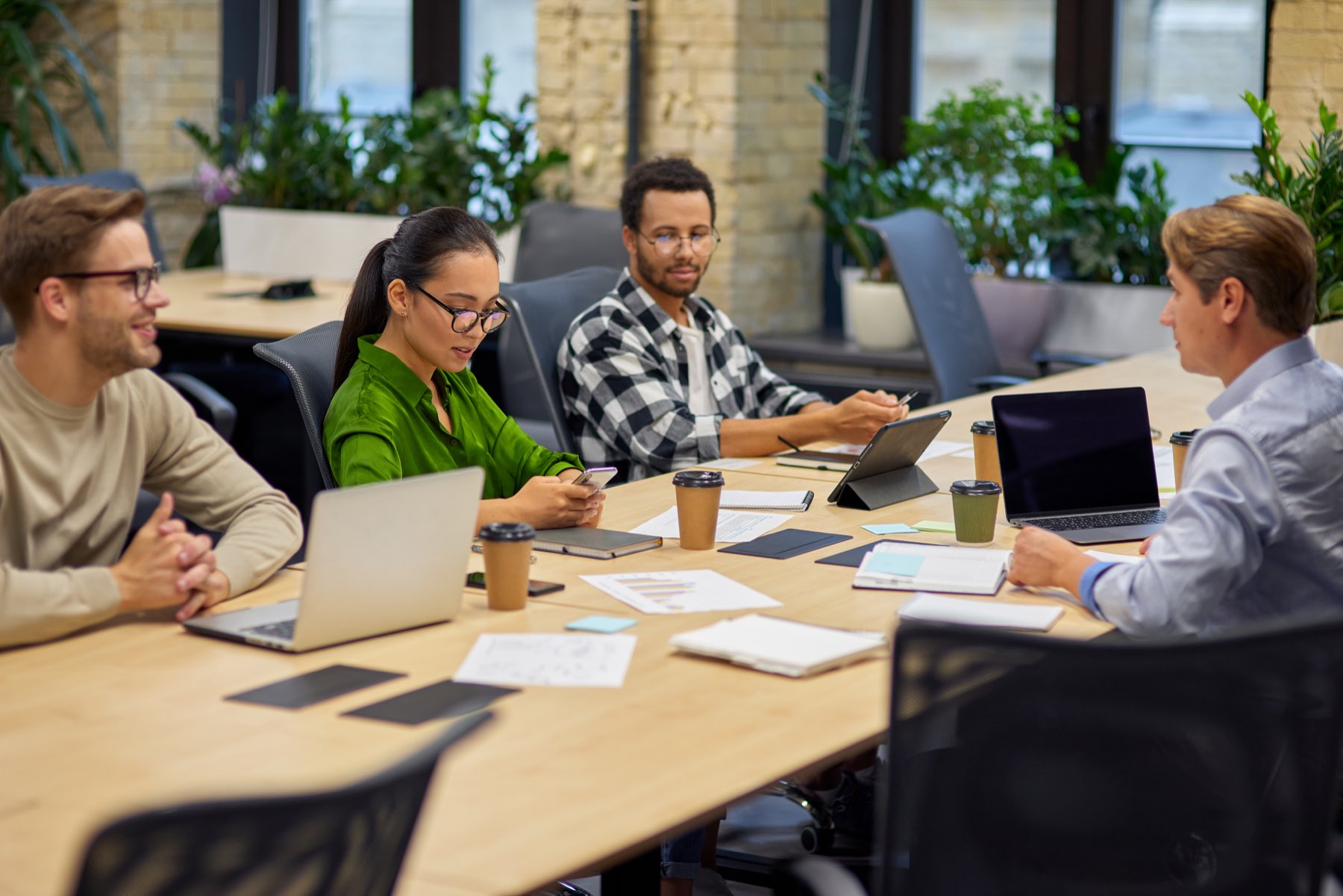 A diverse team reviewing work together over laptops and coffee